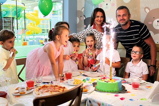 Děti a dospělí u slavnostního stolu s dortem a prskavkou na oslavě narozenin