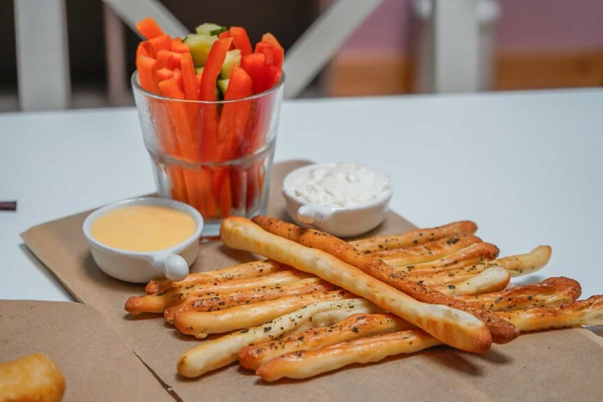 Tyčinky z listového těsta s bylinkami, zeleninové hranolky a omáčky na dřevěném prkénku